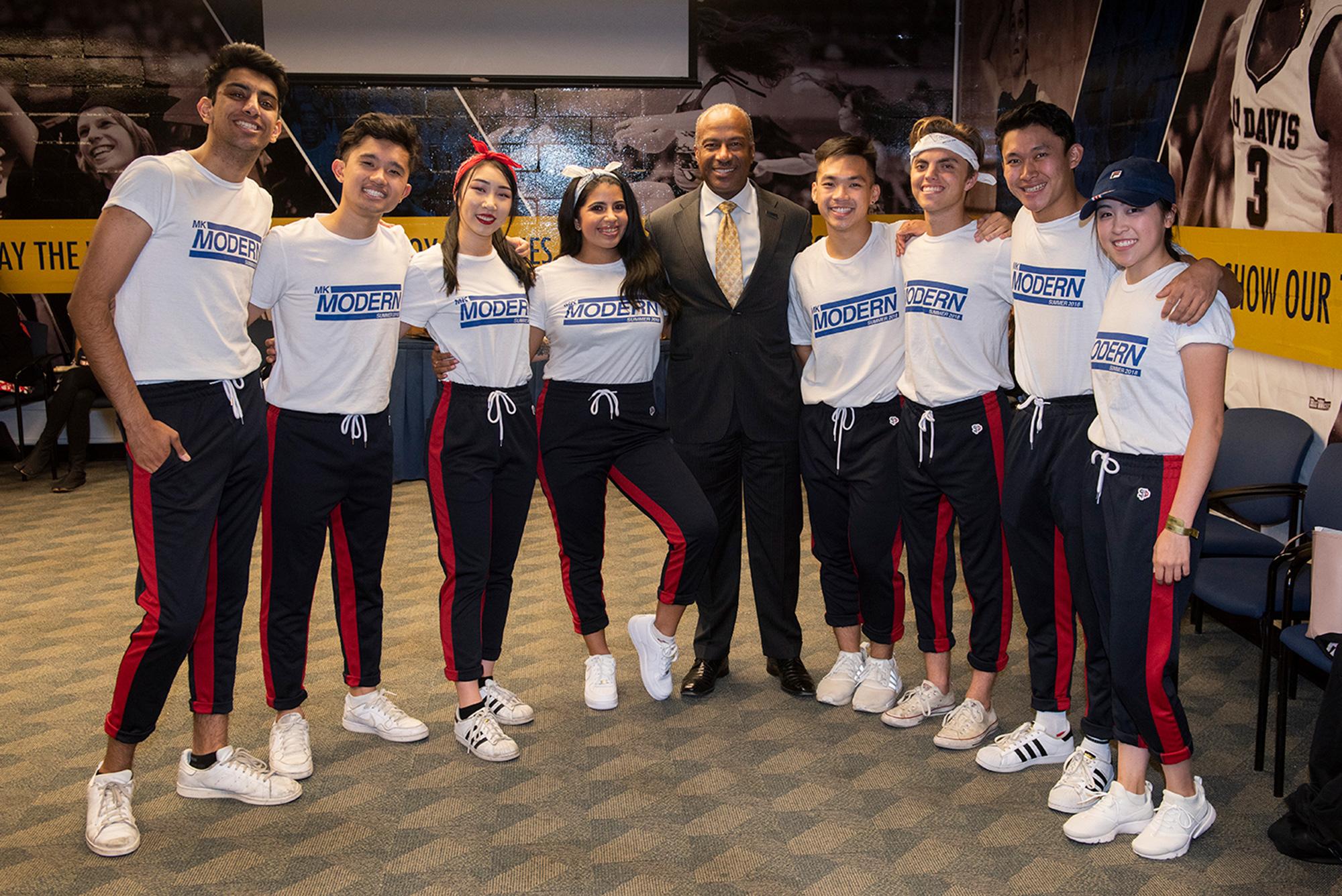 UC Davis Chancellor Gary May, wearing a suit and patterned tie, poses with the MK Modern Dance group before the start of their performance at the Fall Welcome event.